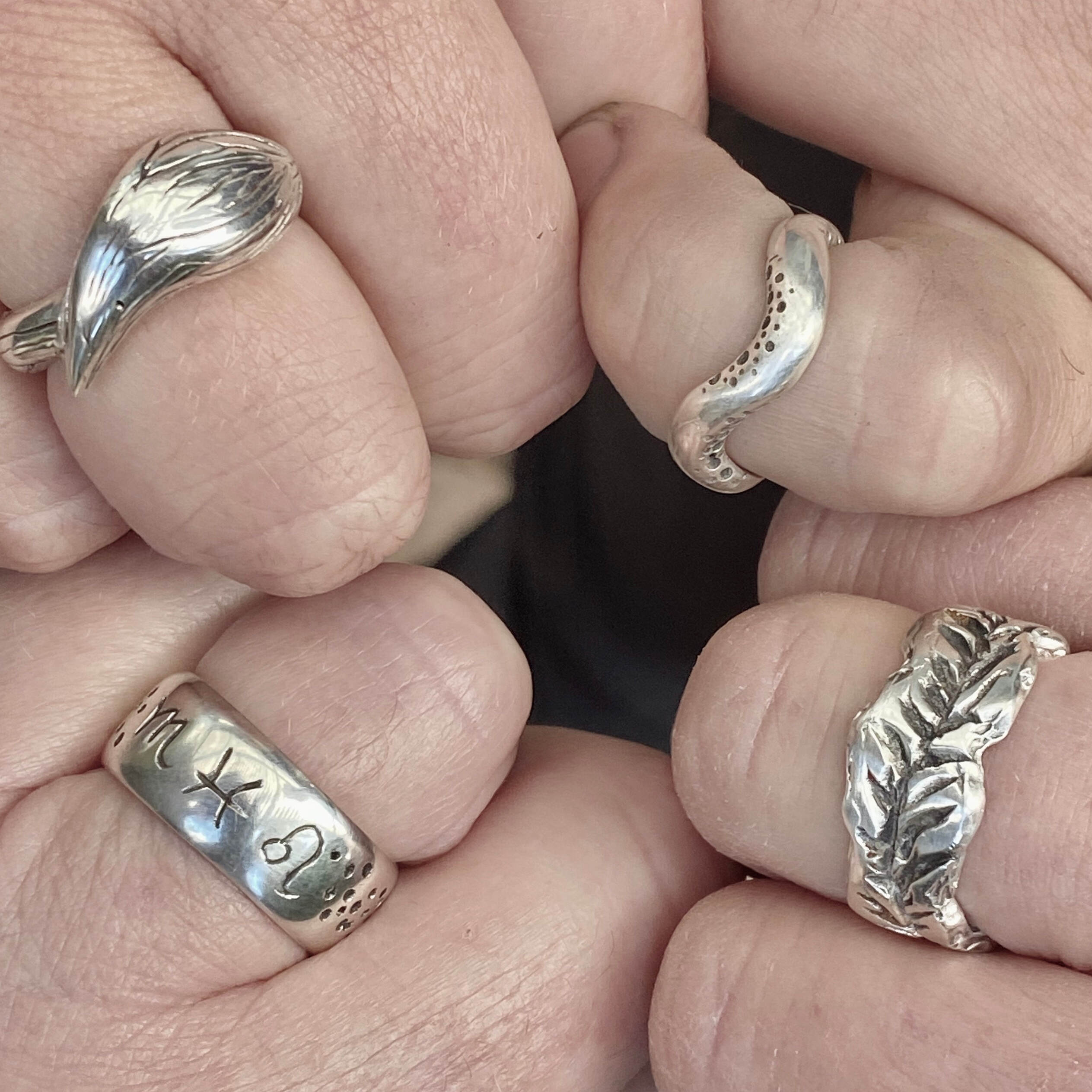 four sterling silver rings on four hands 