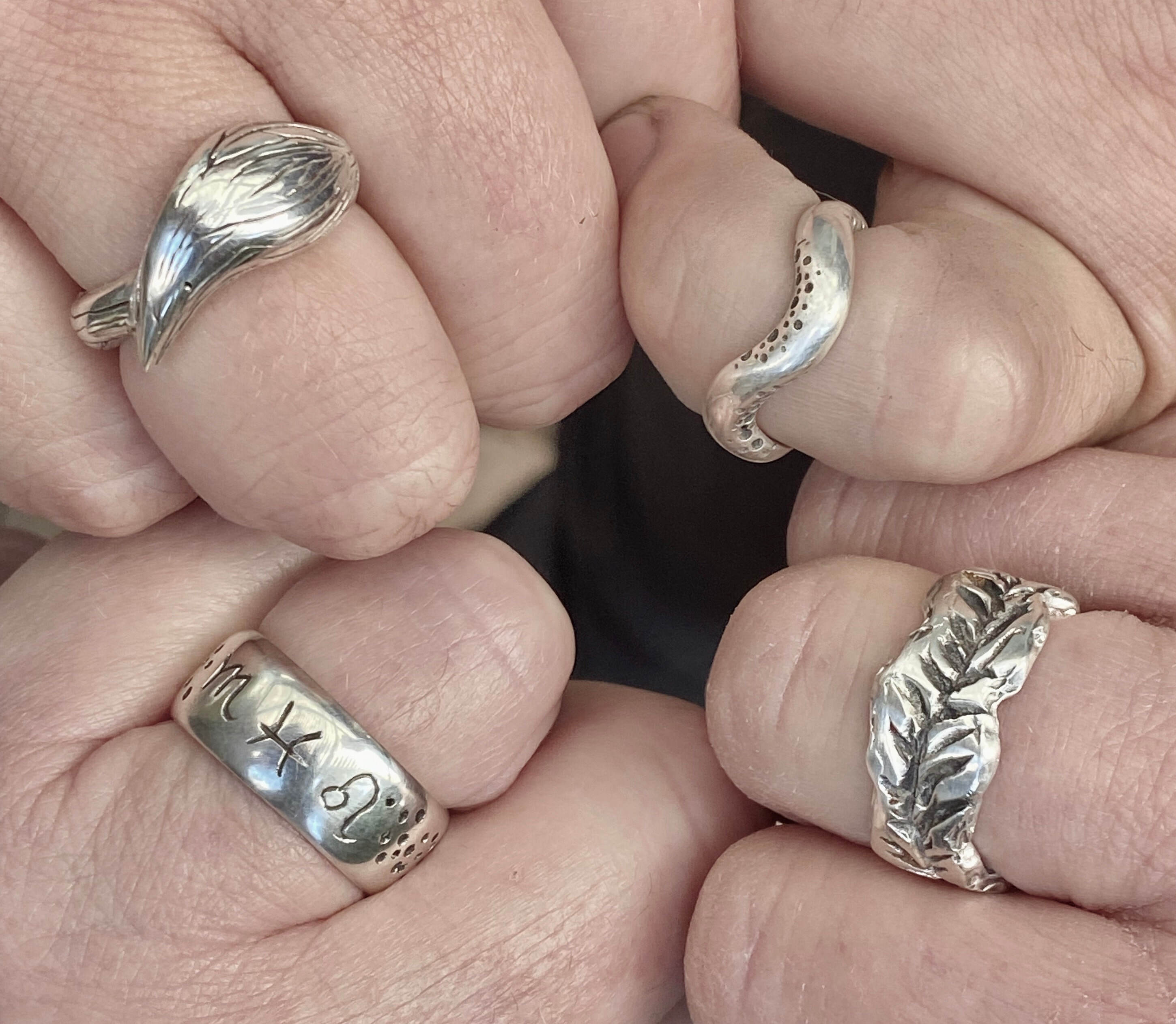 four sterling silver rings on four hands 