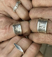 four different sterling silver rings on four hands 